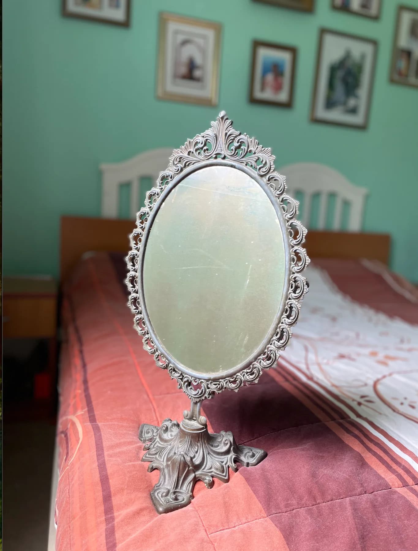 Original ornate oval mirror standing on a bed in a family bedroom.
